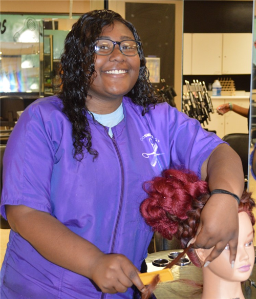 Cosmetology student styling hair on a manikin 